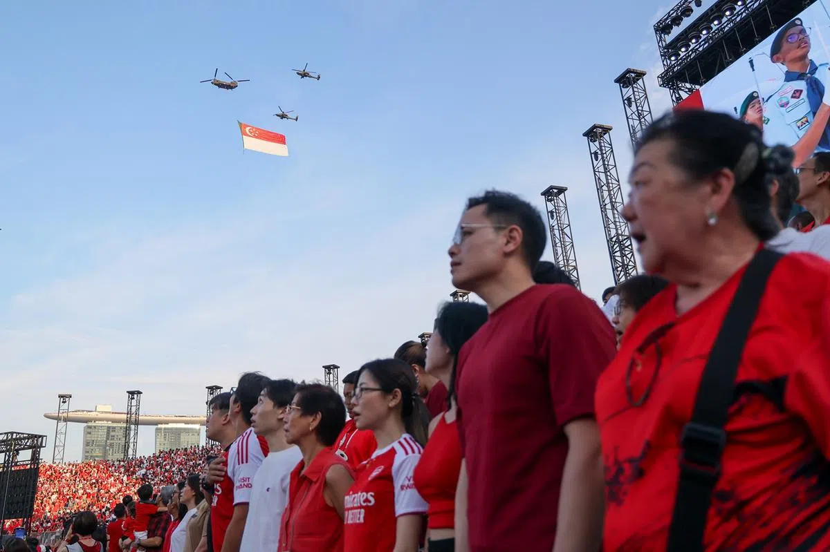国庆庆典上众人齐唱新加坡国歌时，国旗从高空飞过。（联合早报）