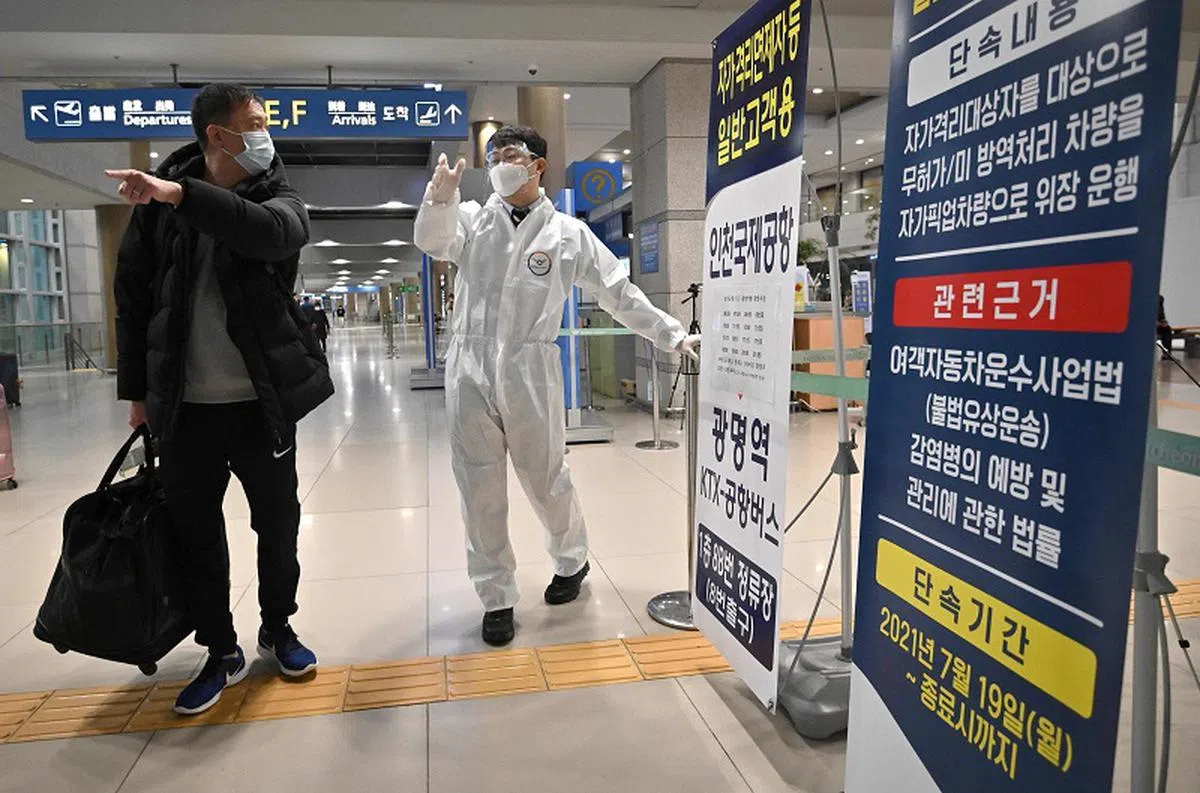 去年11月，韩国还未全面解除边境管控，仁川国际机场的工作人员指引入境旅客。（法新社）