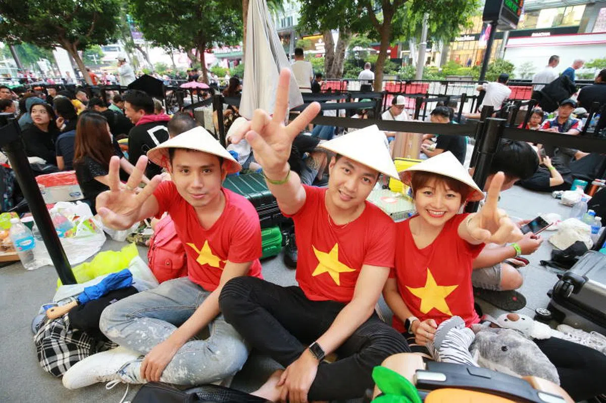  黎莱恩（中）和两名友人身穿印有越南标志的体恤，头戴越南传统草帽，成功排在乌节路苹果手机专卖店队伍的前三名。（联合晚报） 