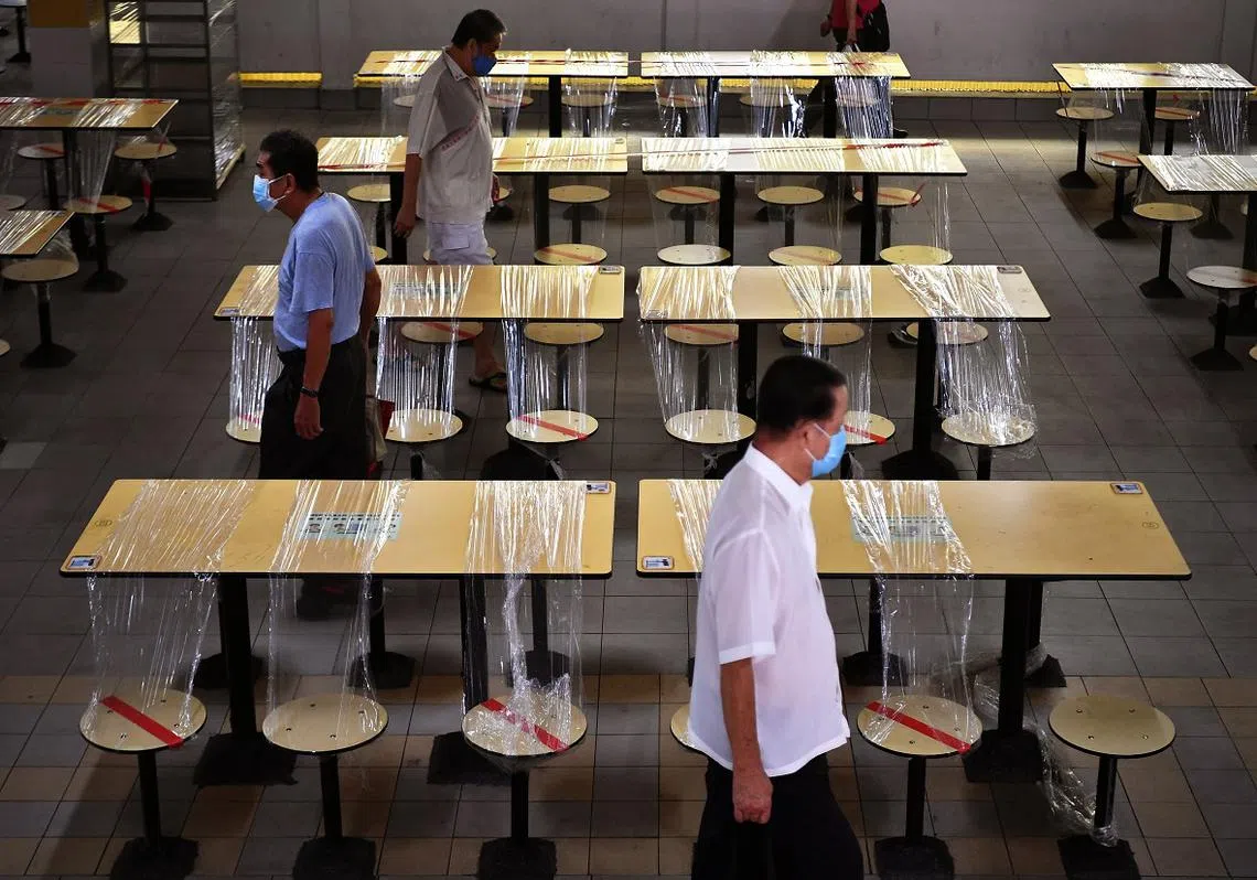 新加坡小贩中心内空无一人、非必要服务暂时关闭，经济深受打击。政府规定大家出门都必须戴口罩，否则将被罚款。（海峡时报）