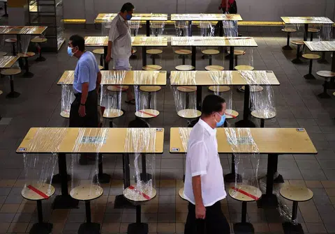 新加坡小贩中心内空无一人、非必要服务暂时关闭，经济深受打击。政府规定大家出门都必须戴口罩，否则将被罚款。（海峡时报）