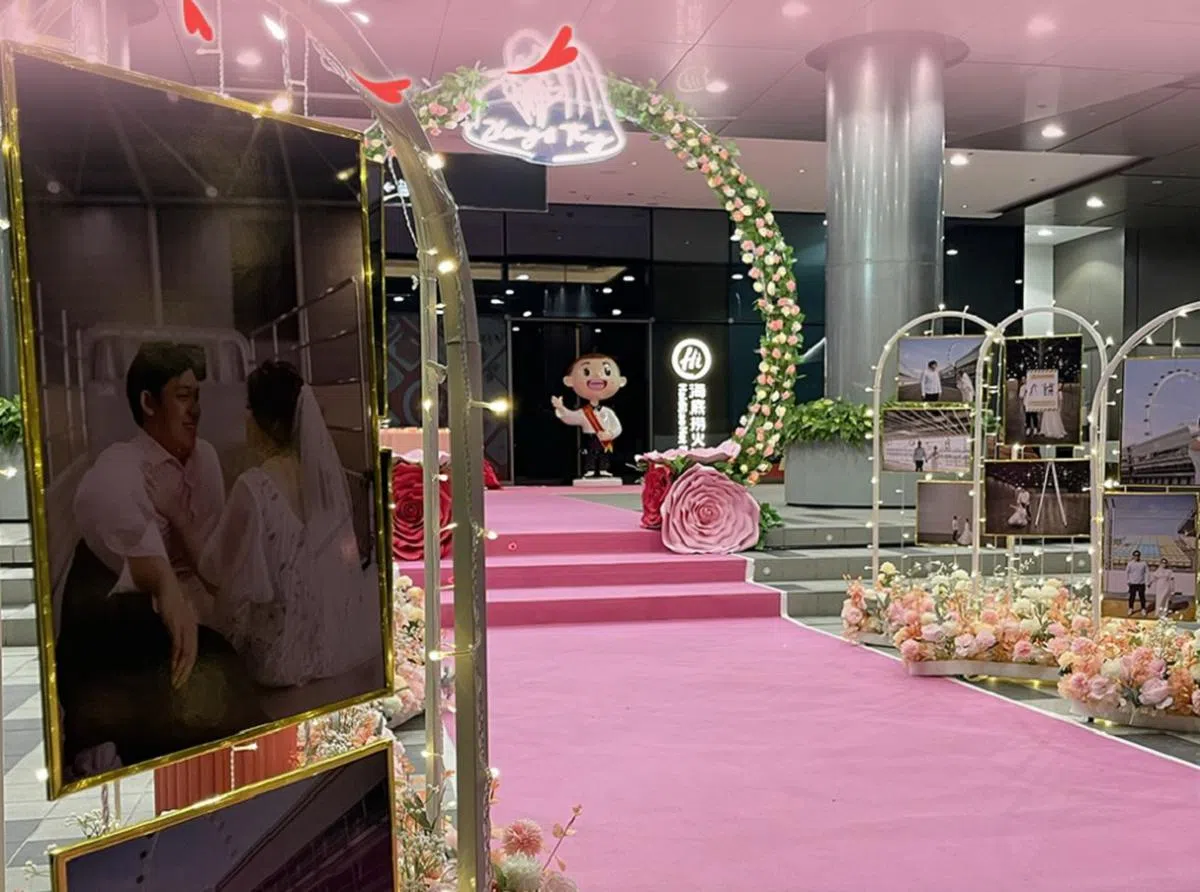 海底捞餐馆入口处摆放着王耀忠与杨雅婷的结婚照，还设立了拱门和铺上粉红色地毯。（滨海广场脸书）
