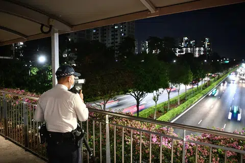 2021年3月27日，一名交警在中央高速公路行人天桥上，用激光测速器执法。（海峡时报）