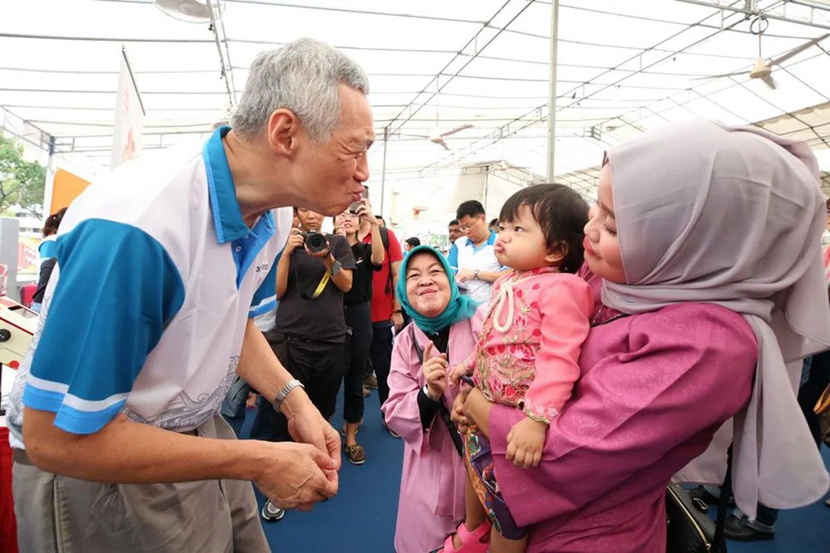  新加坡总理李显龙走基层与小女孩做出一样逗趣的表情。（李显龙面簿） 