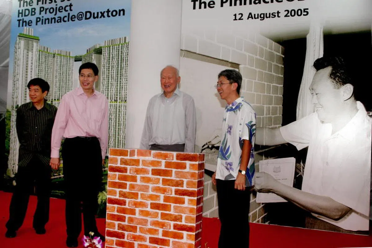  2005年8月12日晚，已故建国总理李光耀重回旧地，在自己于1963年为达士敦坪的首两座组屋主持奠基仪式的照片前，为达士敦坪摩天组屋“达士岭”主持奠基仪式。左一是时任卫生部长兼丹戎巴葛集选区议员许文远、左二是时任建屋发展局局长吕德耀、右一是时任国防部兼环境及水源部高级政务次长兼丹戎巴葛集选区议员顾蔡矶。（联合早报档案照） 