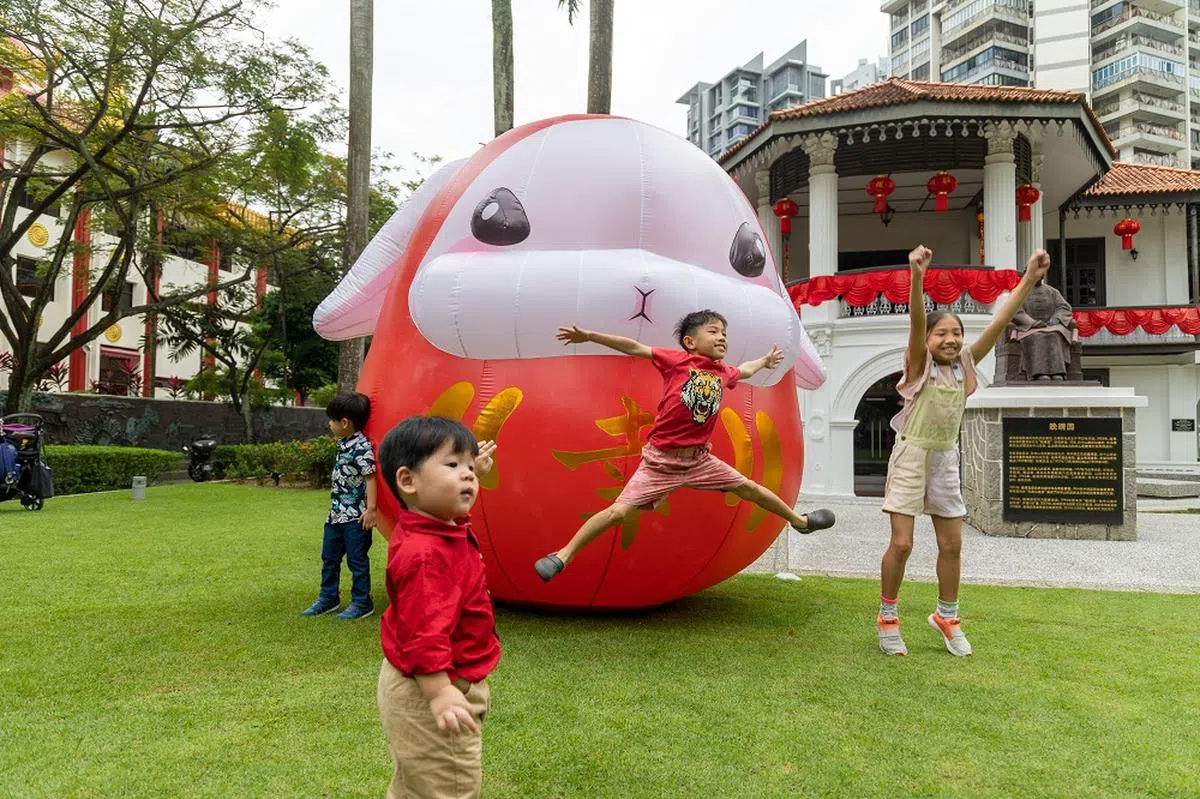 晚晴园草坪上的“幸福比比兔”吸引到不少小朋友围着它玩闹。（联合早报）
