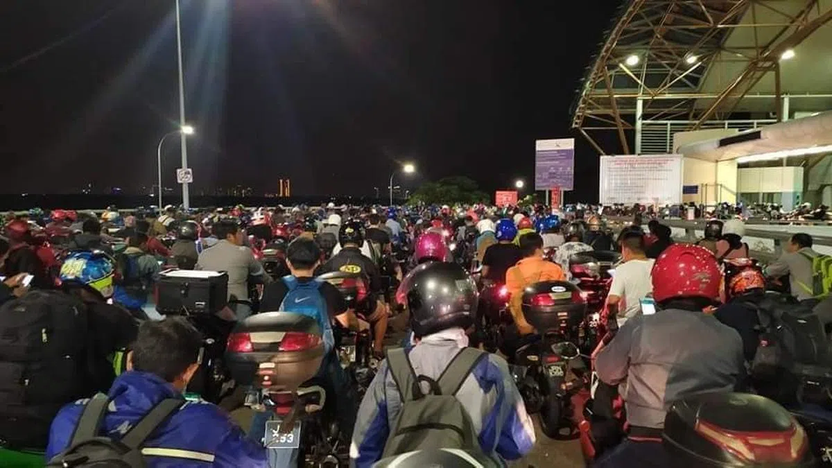 许多马国客工骑着摩托车在等待通关，赶在3月18日凌晨之前进入新加坡。（面簿）