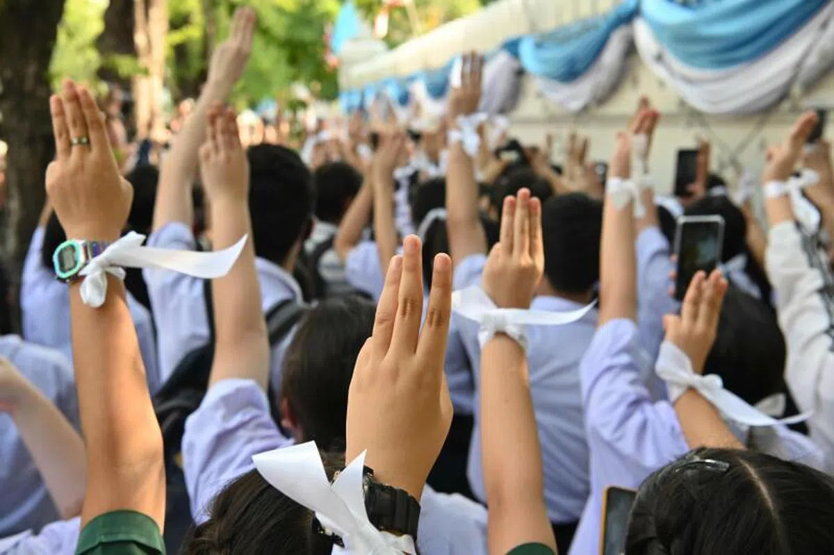  示威者扣上白丝带，并举起来自电影《饥饿游戏》中象征反抗极权与独裁的三指手势，宣泄对政府的不满。（法新社） 