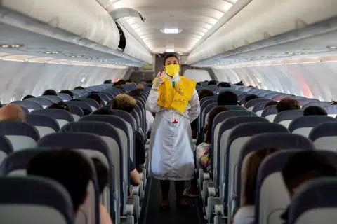 戴着口罩的空服人员为乘客讲解逃生程序。（路透社）