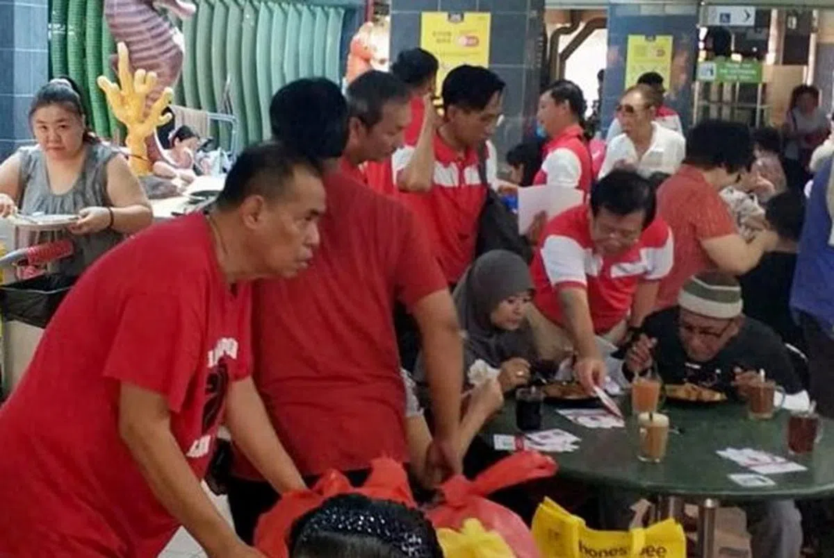  穿红衣服的前进党党员，从某个角度看，很像是在骚扰那些享用美食的公众。（吴作栋面簿） 