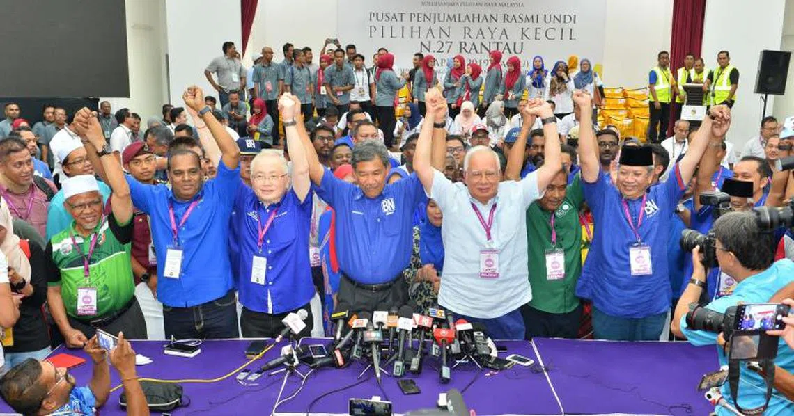 国阵在晏斗补选获胜，莫哈末哈山（中）与前首相纳吉（站者右三） 、马华总会长魏家祥（站者左三）等人高举双手庆祝。（星洲日报）