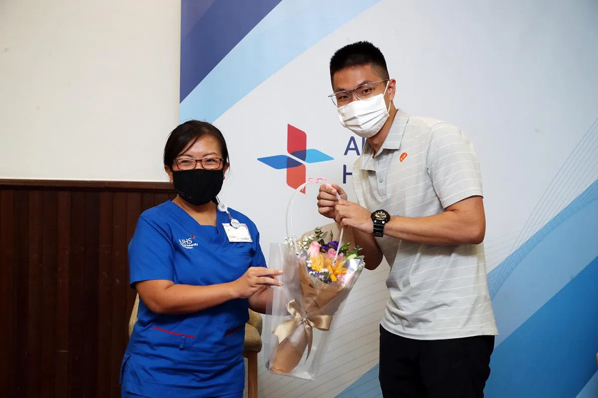 亚历山大医院第一位冠病康复病患于2021年再回医院，送向日葵给时任护士长李桂香。（联合早报）
