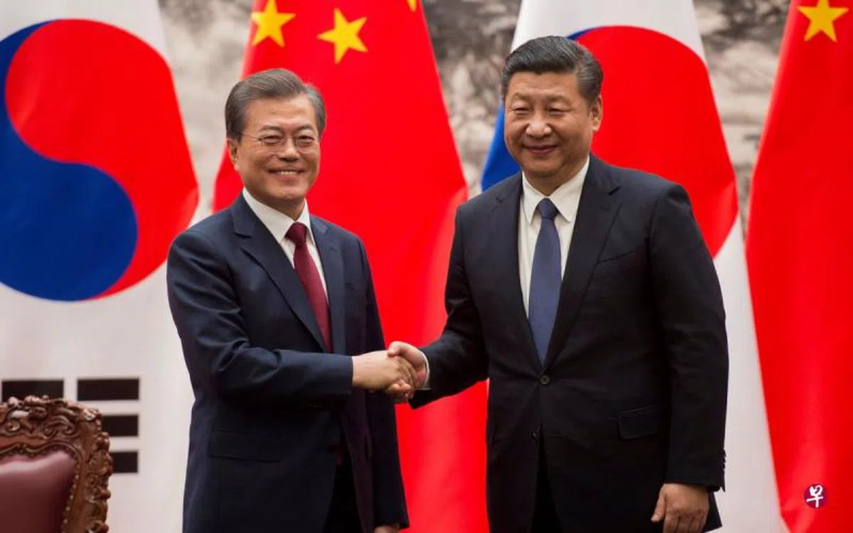  中国国家主席习近平（右）在北京人民大会堂同赴华进行国事访问的韩国总统文在寅共同见证双边合作文件的签署后握手致意。（路透社） 
