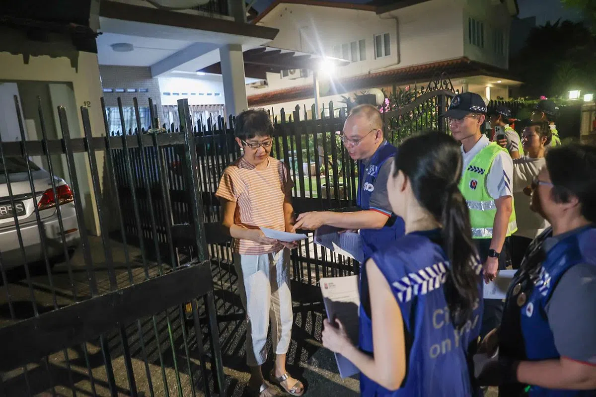 市民巡逻小组挨家挨户，提醒私宅居民提高警惕。（联合早报）