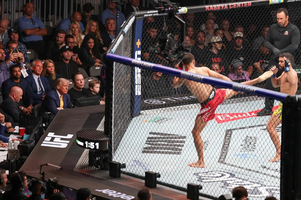 特朗普4月12日晚上现身迈阿密卡赛亚中心，观看终极格斗冠军赛（UFC），坐在他左手边的是世界首富、特斯拉首席执行官马斯克与儿子。（法新社）
