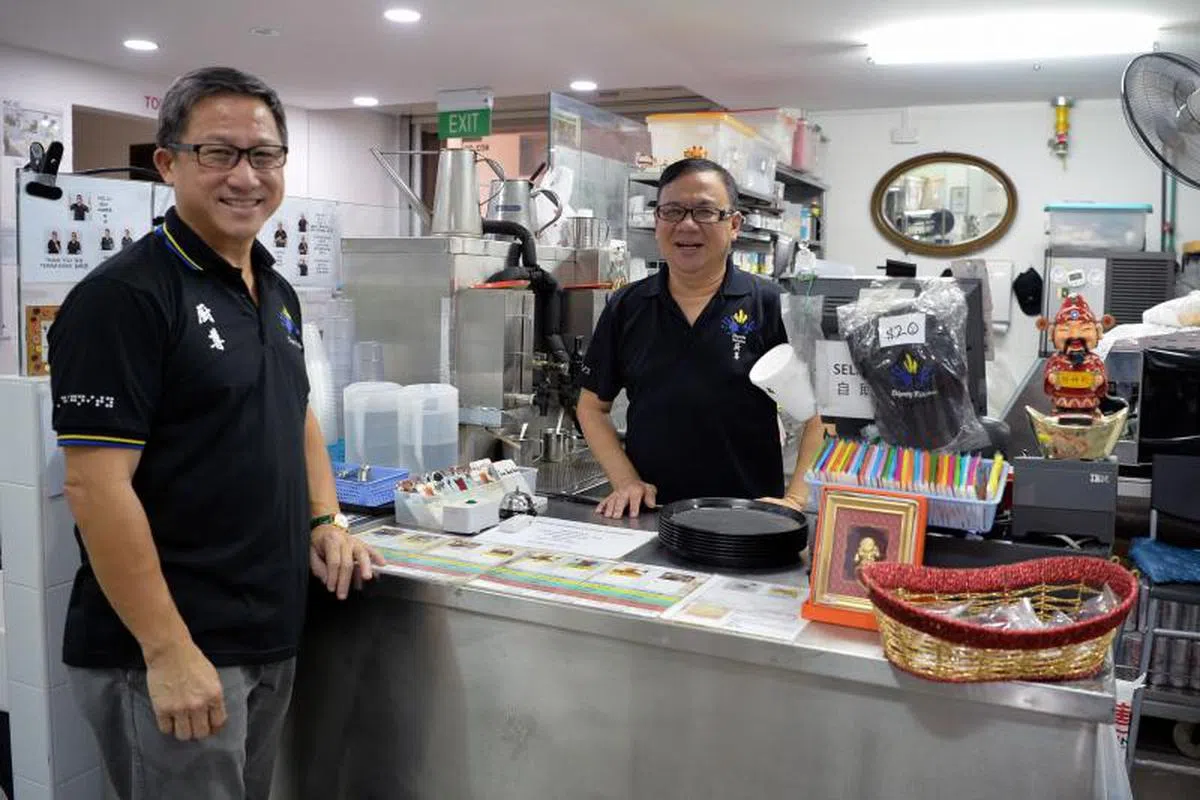  “厨尊”里设有一个由残障人士经营的小食阁，其中茶水档是由两名聋哑人士负责看顾。创办于2010年的“厨尊”是个小贩学徒计划，专门培训残障者成为小贩。在茶水档工作的失聪残障员工王招锭（右）感激老板许承俊（厨尊创办人，左）给予机会，让他们有一技之长，残而不废。（联合晚报） 