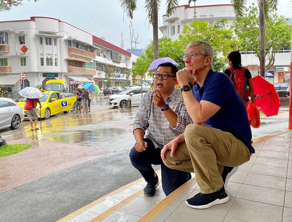  苏建隆带着库克半蹲半跪来欣赏中峇鲁地区的政府组屋。（Darren Soh） 