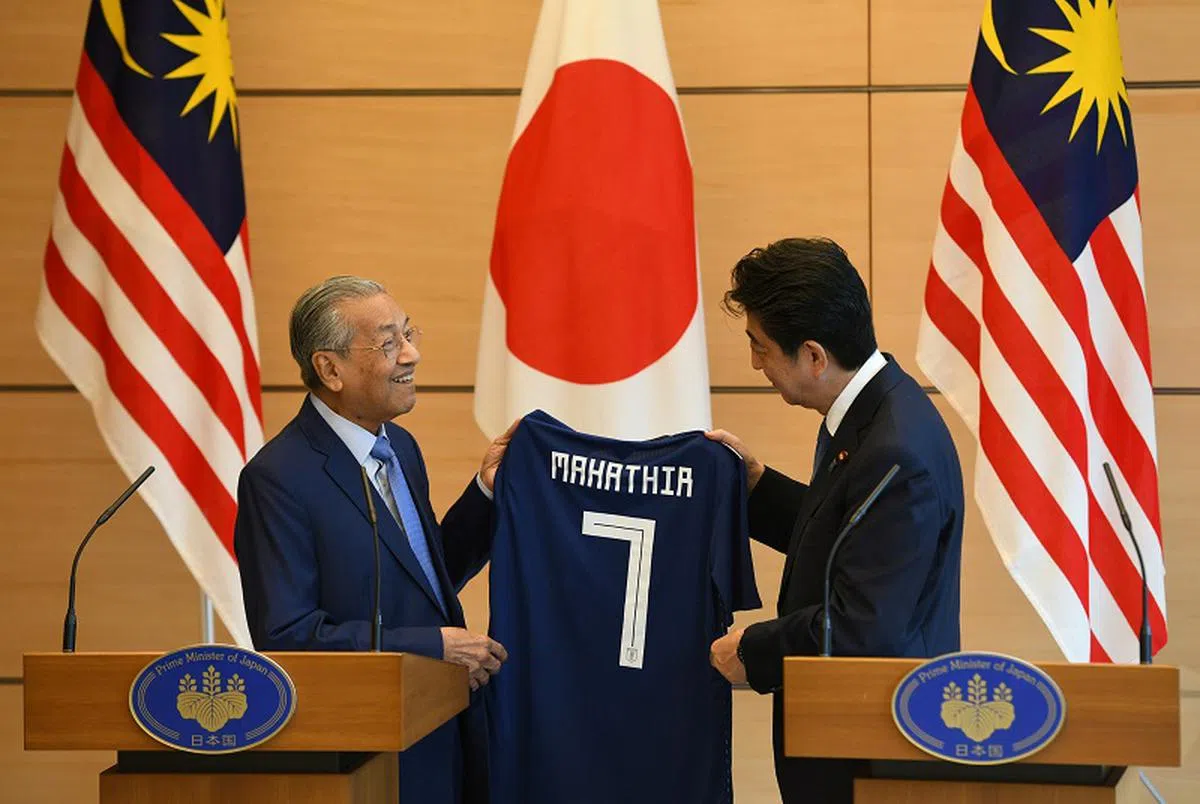  日本首相安倍晋三（右）将一件印有马哈迪英文名字的球衣赠予马哈迪。（法新社） 