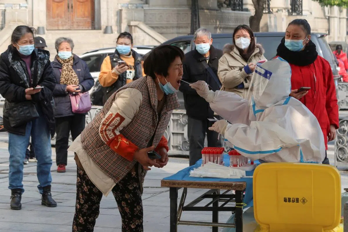 穿着防护服的医护人员为一名妇女进行核酸检测。（路透社）