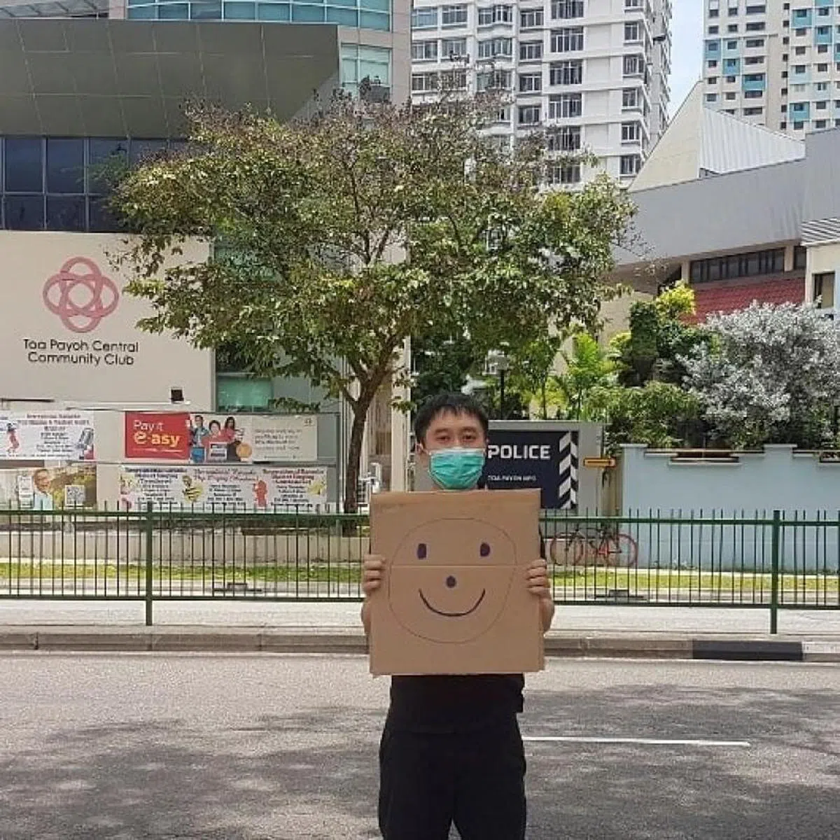  今年三月，社运分子范国瀚在一间警局附近，举了个牌子显现一个绘制的笑脸抗议。（路透社） 
