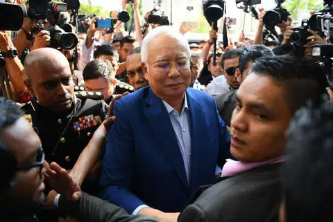 马国前首相纳吉今早抵达反贪会总部录口供，被大批媒体包围。（法新社）