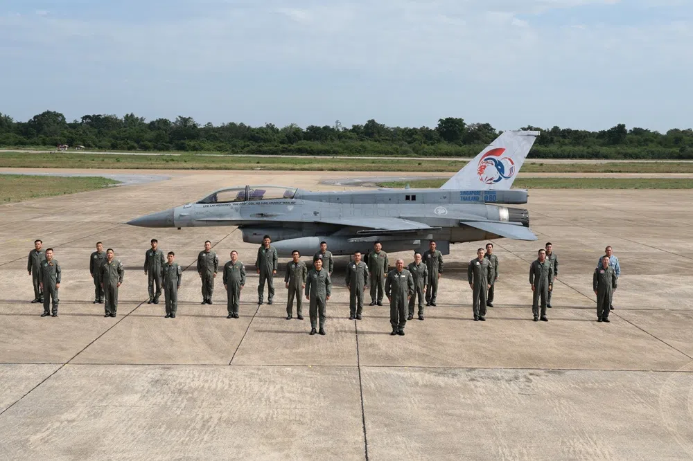 参与今年7月联合演习的新加坡空军和泰国空军军人在漆上纪念图案的战机前列队，摄于泰国呵叻空军基地。