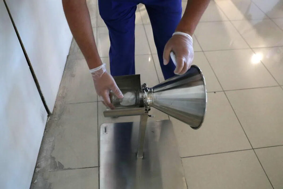  一名医疗人员在容器中放入病毒样本，训练缉毒犬辨别冠病病毒。（路透社） 