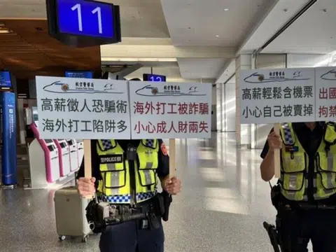 台湾警员在桃园机场高举“提防诈骗”标语，提醒有意前往柬埔寨的民众避免陷入人口贩卖陷阱。（今周刊）