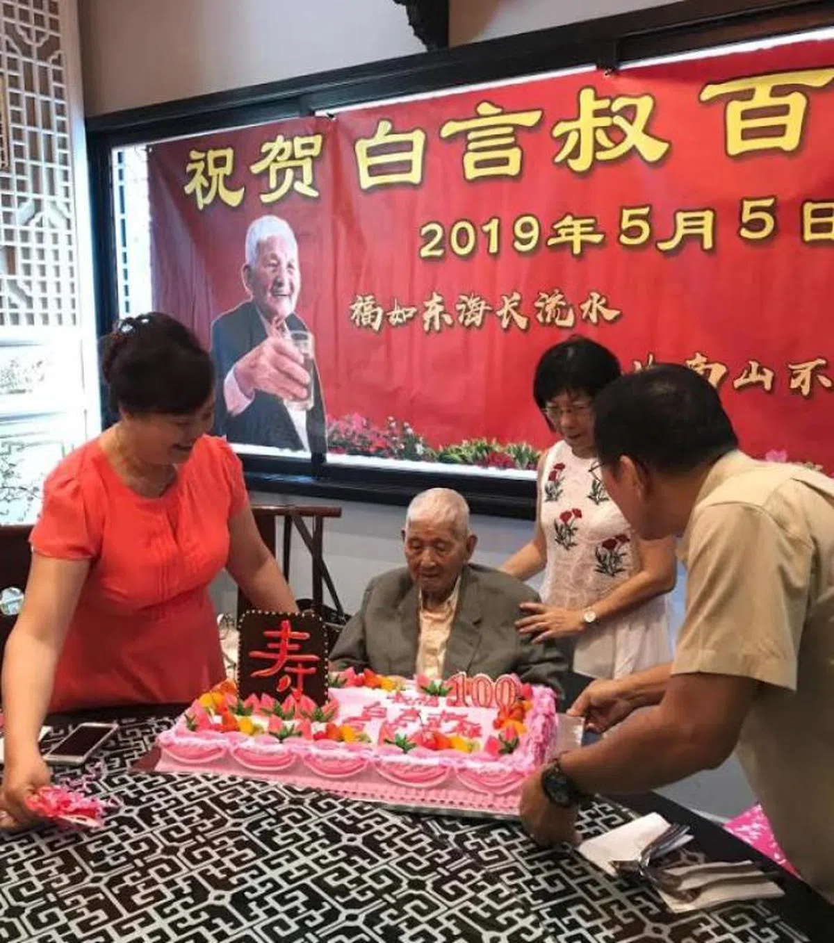  白言今年的寿宴上，筹委会为白言准备了写着“白言叔百岁吉祥” 的大蛋糕和寿桃。（档案照） 