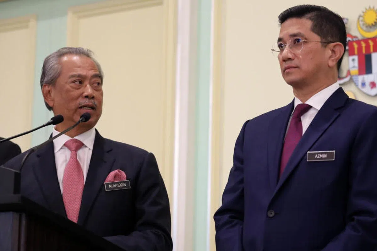  马来西亚首相慕尤丁在一场记者会上望了一眼高级部长阿兹敏。（路透社） 