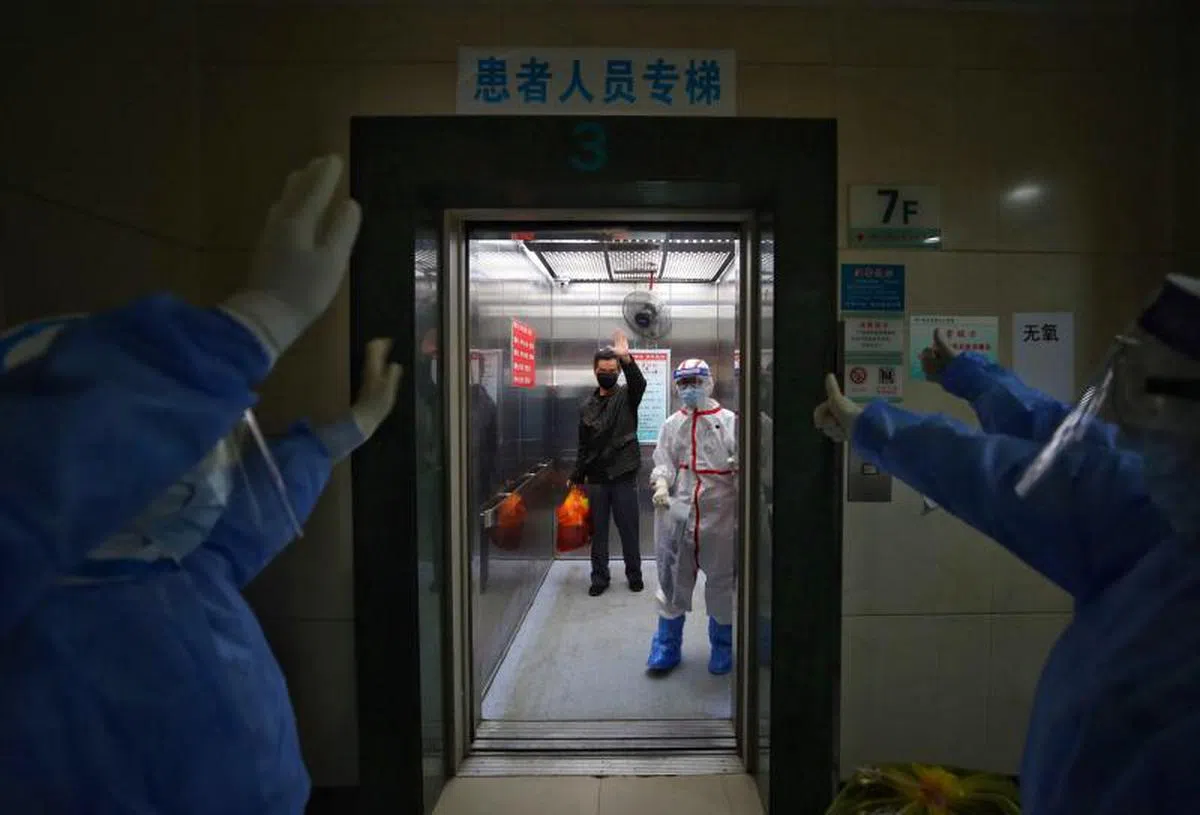  一名冠病康复者向武汉市红十字会医院的医护人员道别。（法新社） 