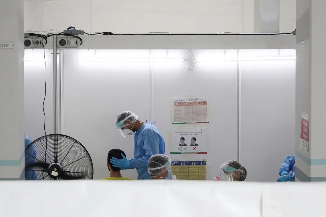 卫生部在2021年5月21至22日为后港8道第506座组屋的405人进行冠病检测，图为一位居民正在接受采检。（联合早报）