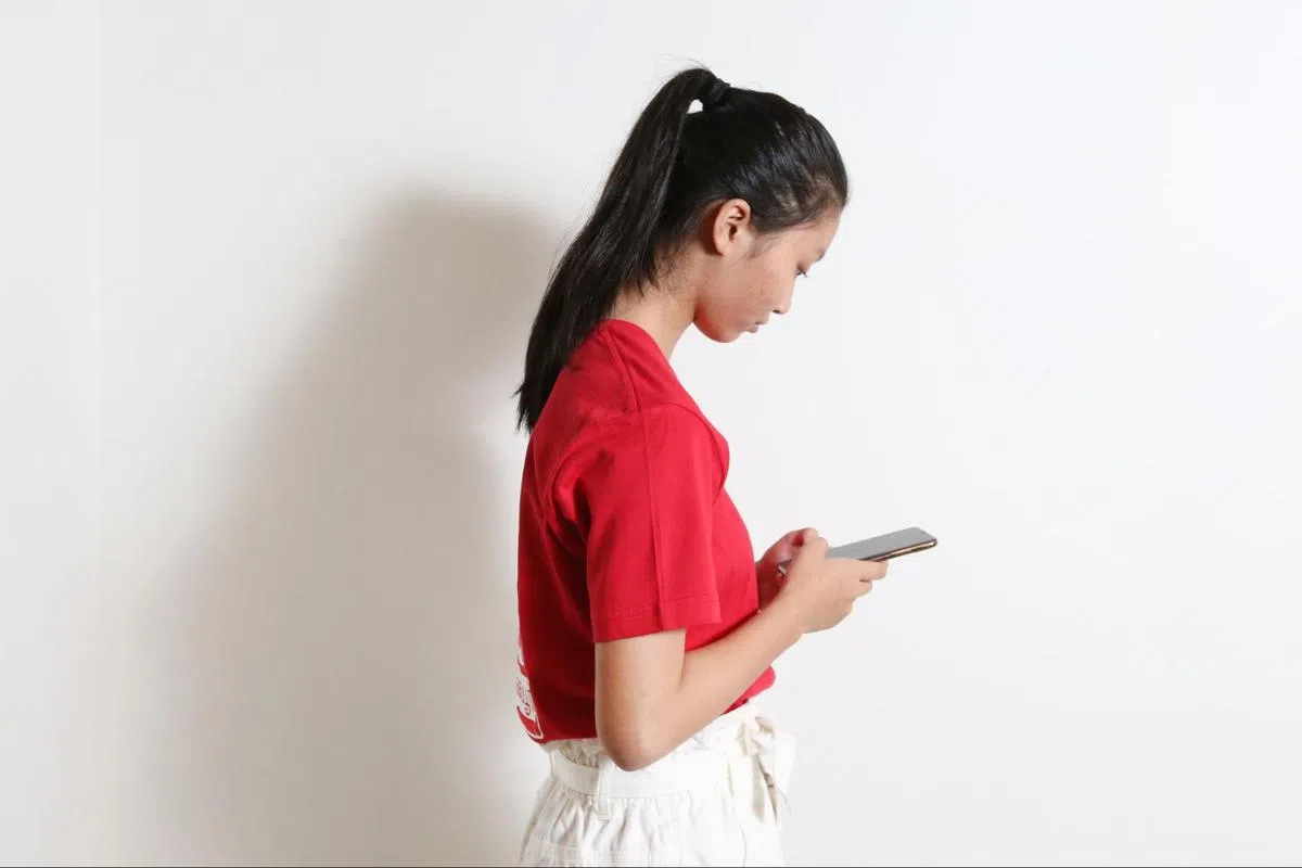 示意图：长期低头使用手机可能导致“科技颈”。（联合早报）