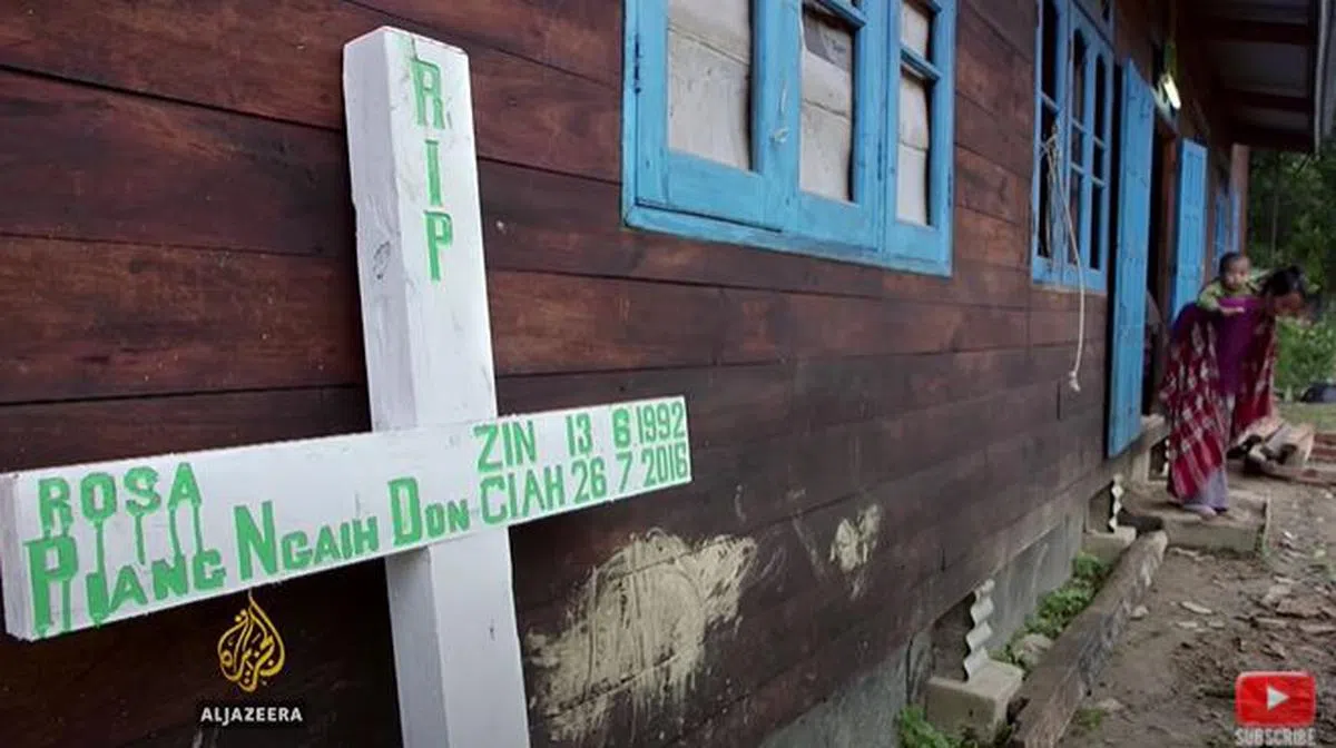  住家外立起一个写着磅艾赫多恩名字的十字架，上面写着的出生日期也是1992年6月13日。年幼的儿子被阿姨背着，仍无法体会母亲逝世的痛苦。（半岛电视台） 