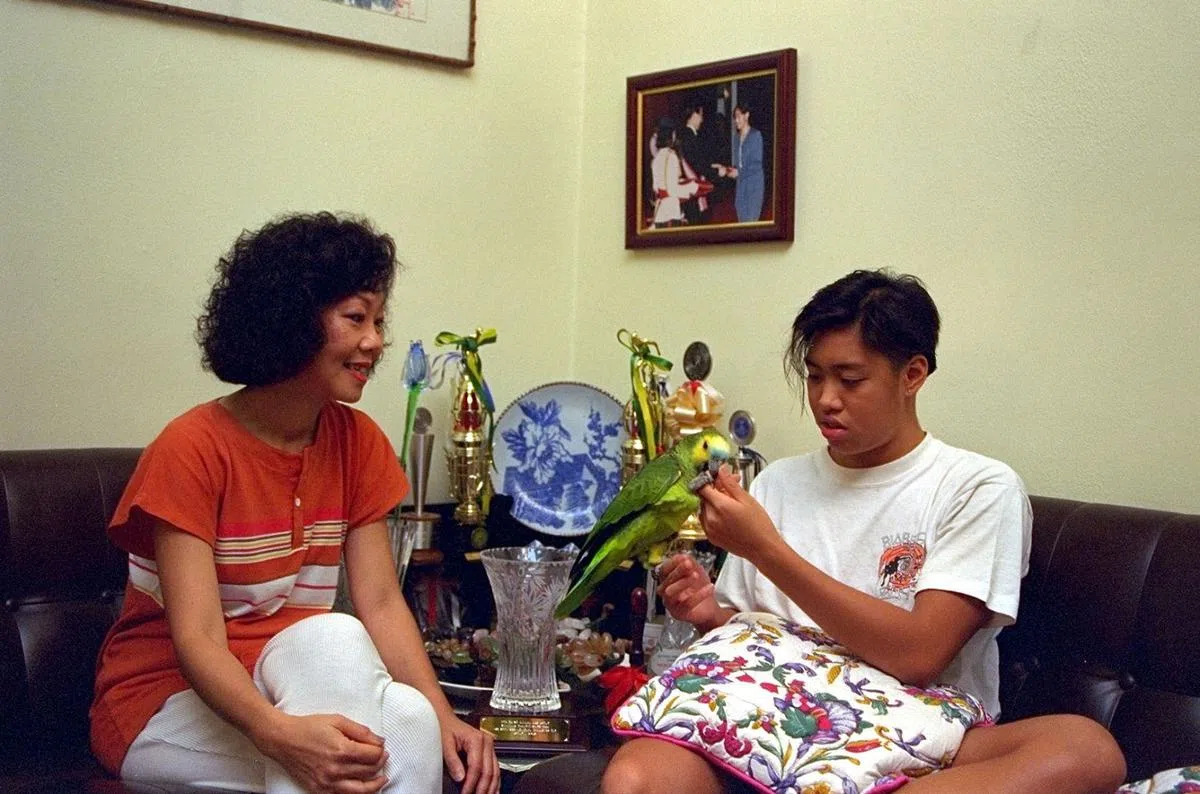 杨玮玲（右）10岁时在全国分龄游泳赛刷新10项大会记录，母亲陈丽珠（左）送她鹦鹉作为奖励。（联合早报）