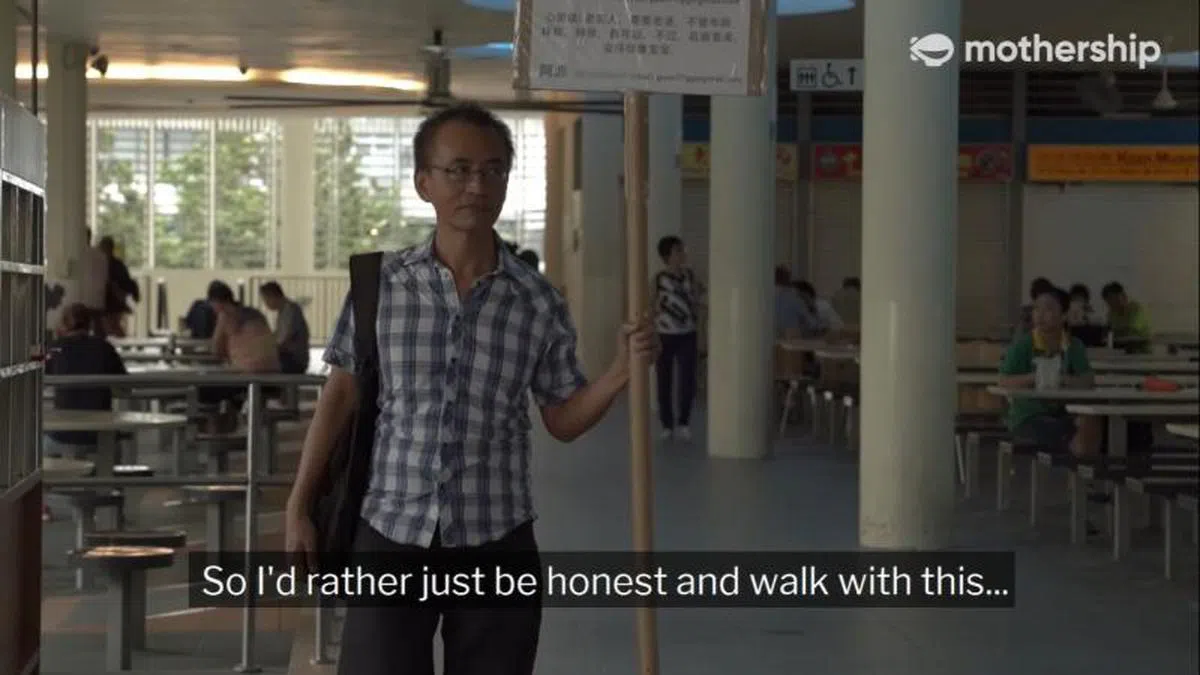  老实的阿源坚持用老实的方式去寻找爱，就连走进小贩中心也不忘举着牌子“找爱”。（慈母舰视频截图） 