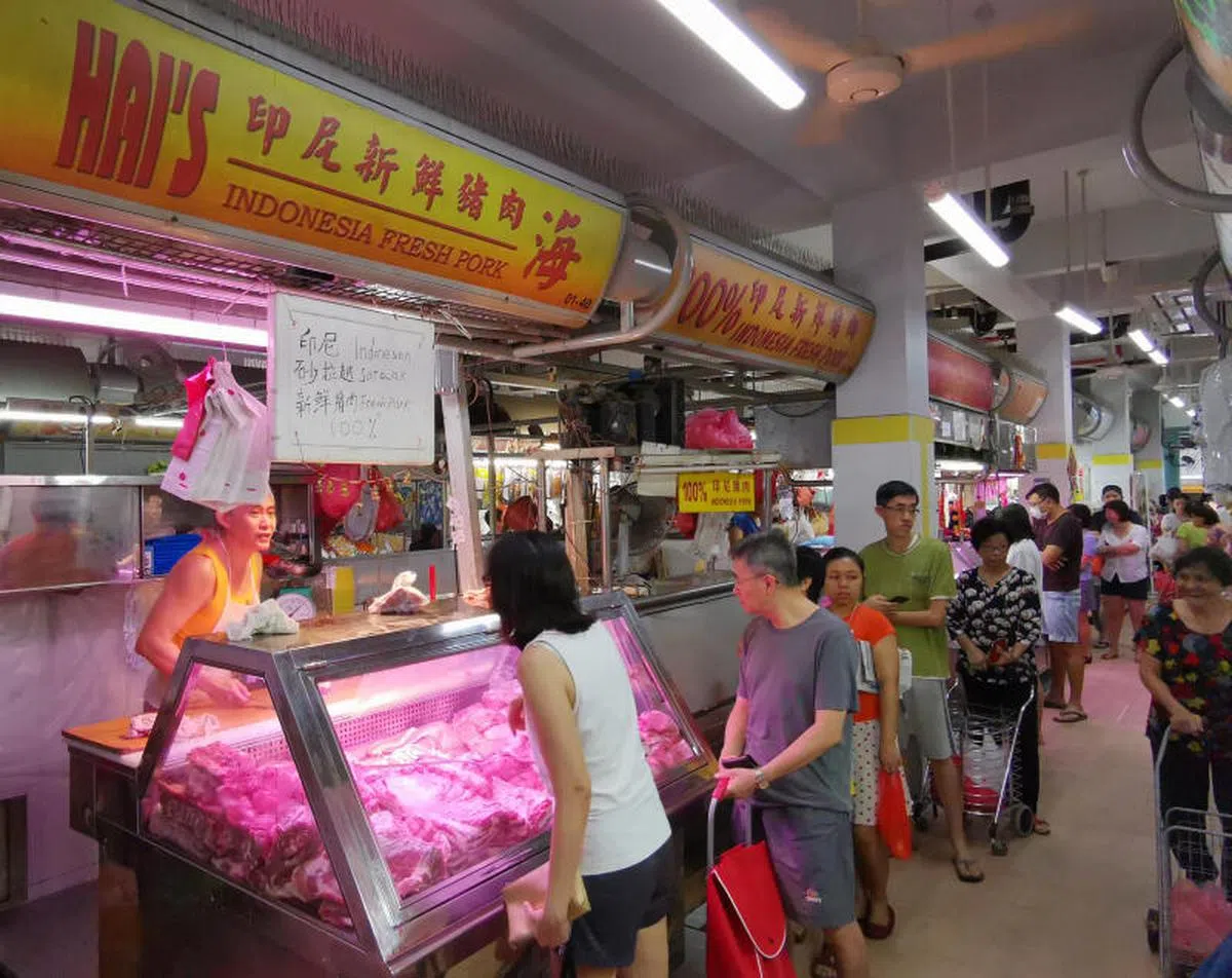 图为民众在巴刹内的猪肉摊位前排队购买新鲜猪肉。（联合早报）