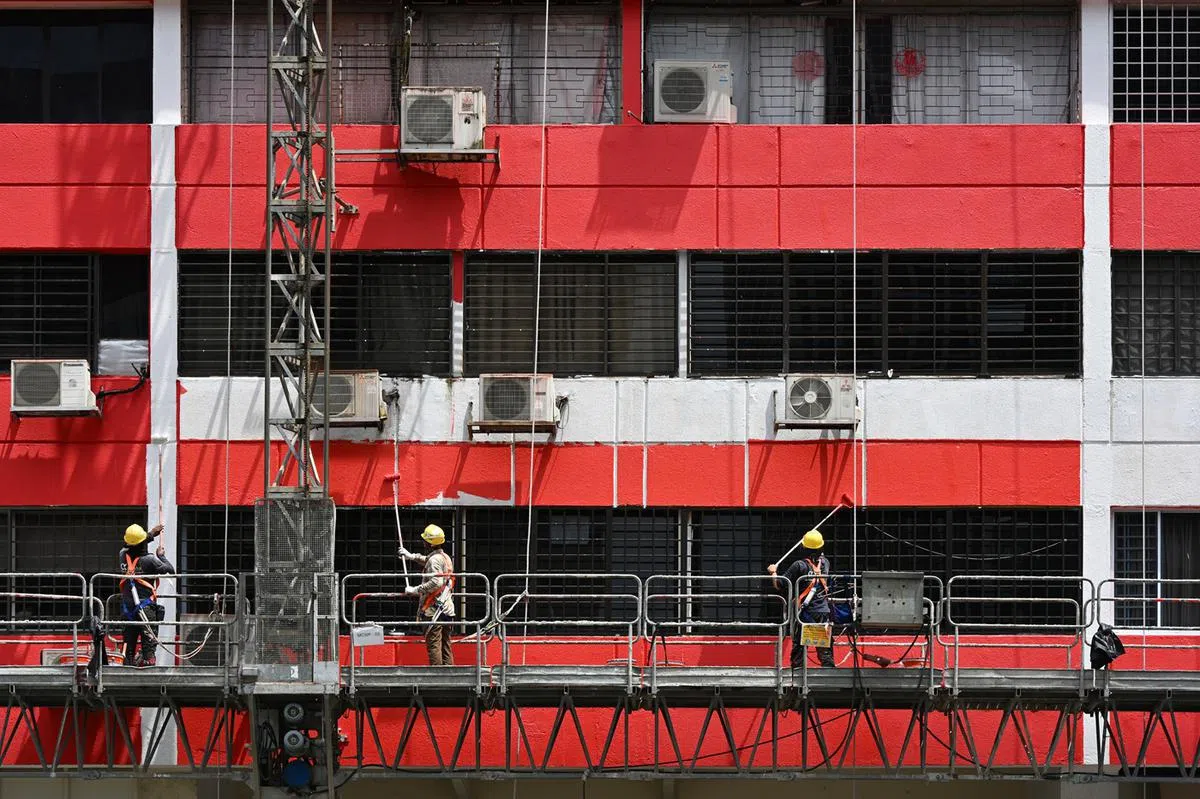 油漆客工在烈日下工作。（海峡时报）