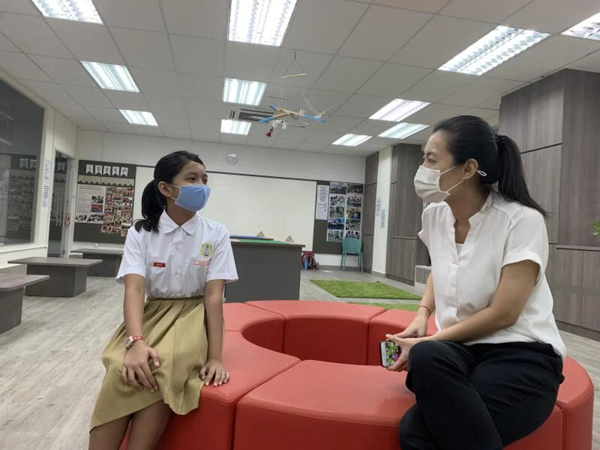  启化小学小五生法莎（左）2019年完成华语会话课，如今能以简单的华语问候语，向校内食堂的摊贩问好。图为法莎与学校华文科目主任徐燕妮交谈。（联合早报） 