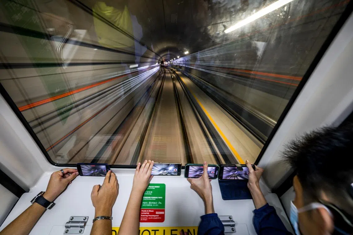 地铁穿越地铁隧道时，站在列车前端的乘客纷纷掏出手机拍摄。（联合早报）