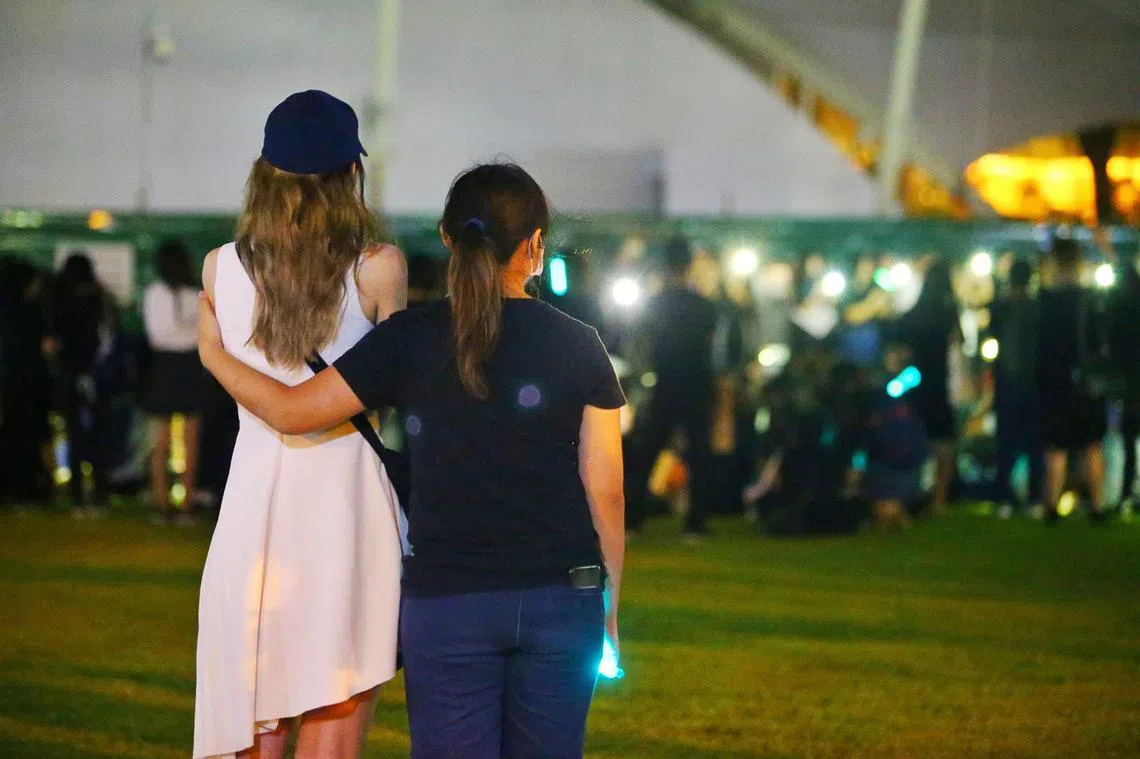 粉丝摇摆手中发光的手机和珍珠湖水蓝荧光棒，纪念钟铉。珍珠湖水蓝是SHINee粉丝会的应援颜色。（海峡时报）