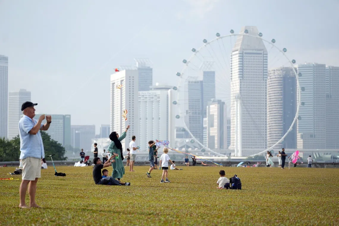 不同种族的人士在滨海堤坝放风筝，度过悠闲的一天。
