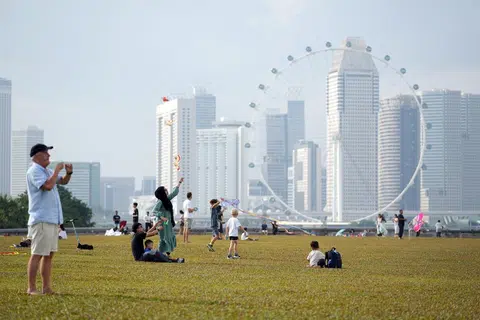 不同种族的人士在滨海堤坝放风筝，度过悠闲的一天。