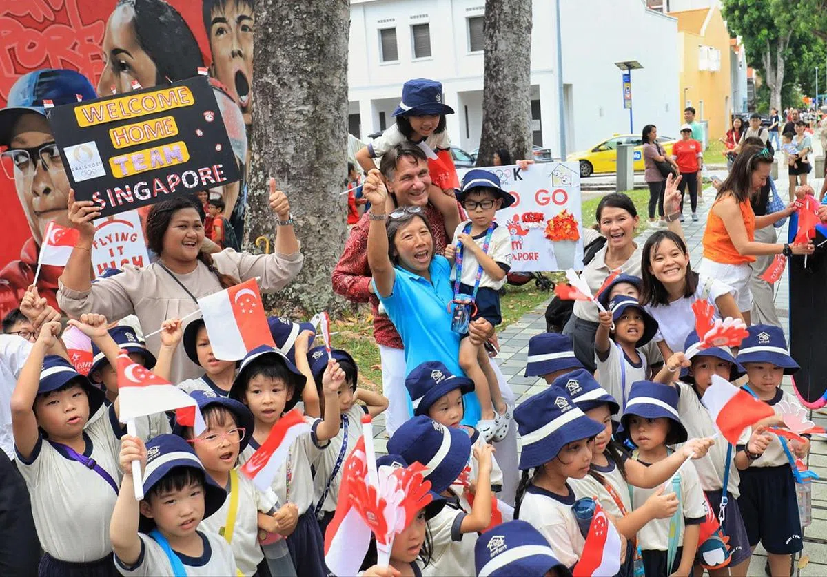 墨士廉的父亲瓦伦丁（身穿深红色长袖上衣）和母亲丁慧卿（身穿蓝色上衣）等待儿子与参与游行的其他新加坡奥运健儿所乘坐的敞篷巴士经过。(联合早报)