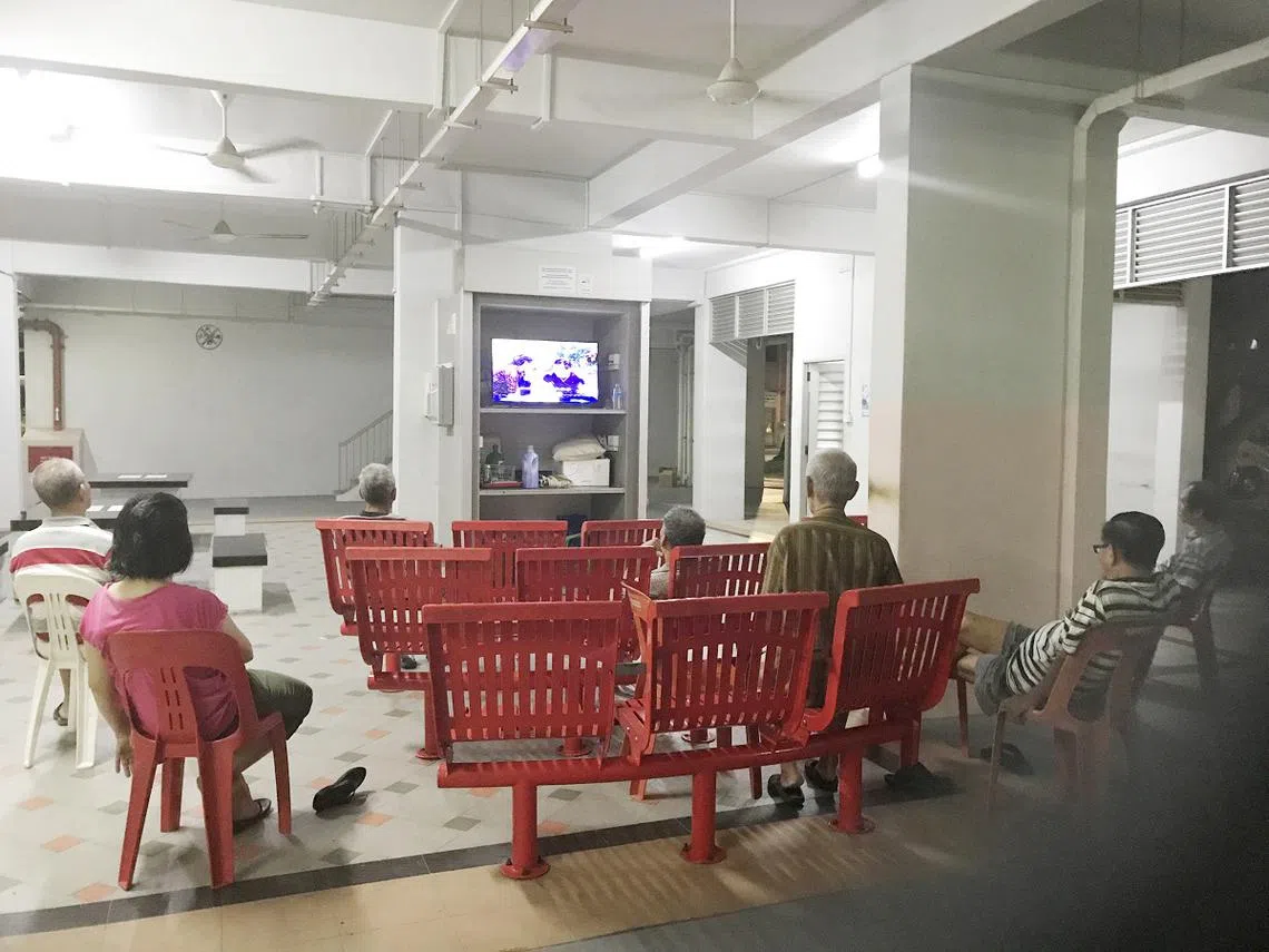 年长人士在组屋楼下的乐龄角落一起看电视。（联合晚报）