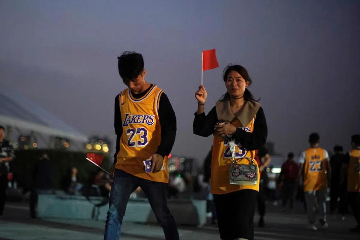  身穿湖人球衣的中国球迷，手举国旗进场观看上海举行的NBA季前赛。 （路透社） 