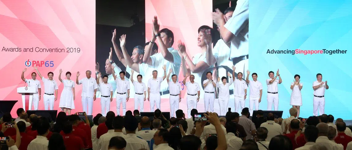 人民行动党中央执行委员会成员在行动党65周年党大会上，向在场的2500名出席者挥手致意。左起为迪舒沙、黄循财、杨莉明、黄永宏、李智陞、王乙康、王瑞杰、李显龙、颜金勇、马善高、陈振声、傅海燕、维文、陈川仁、黄志明、英兰妮和司徒宇斌。（联合早报）