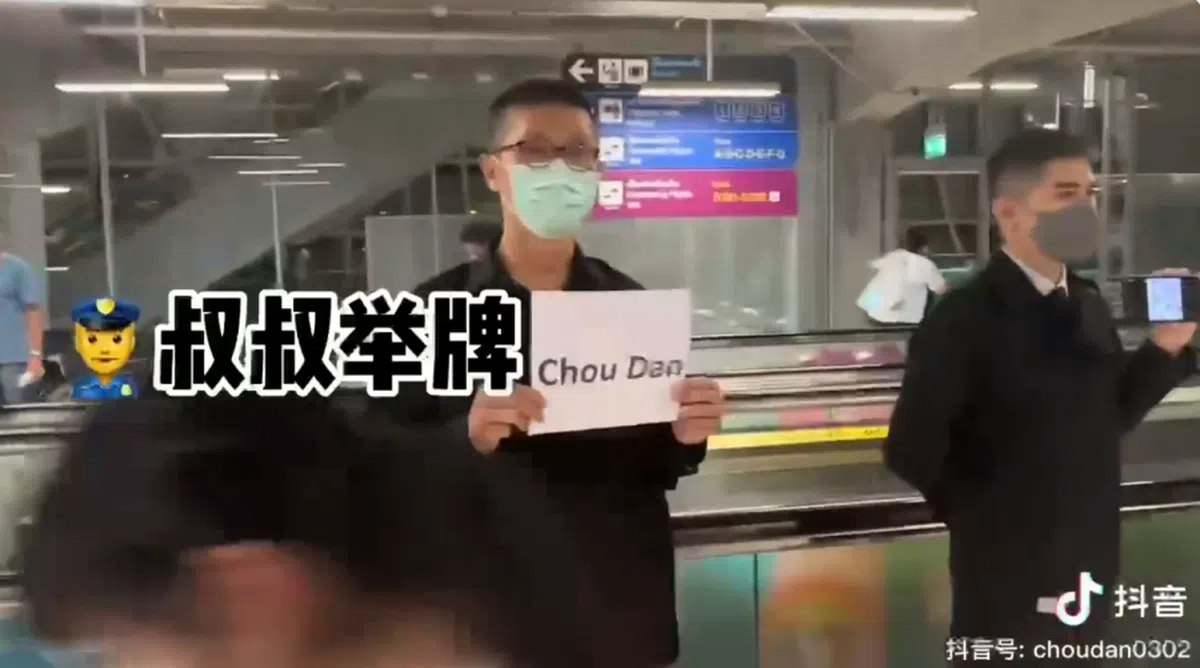 一名警察在下机处举牌等候女网红。（视频截图）