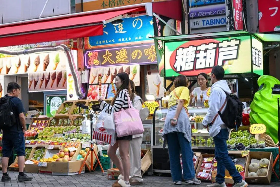 道顿堀随处可见的“来自大连的味道”以及“传统冰糖葫芦”等中文招牌。（日本经济新闻）