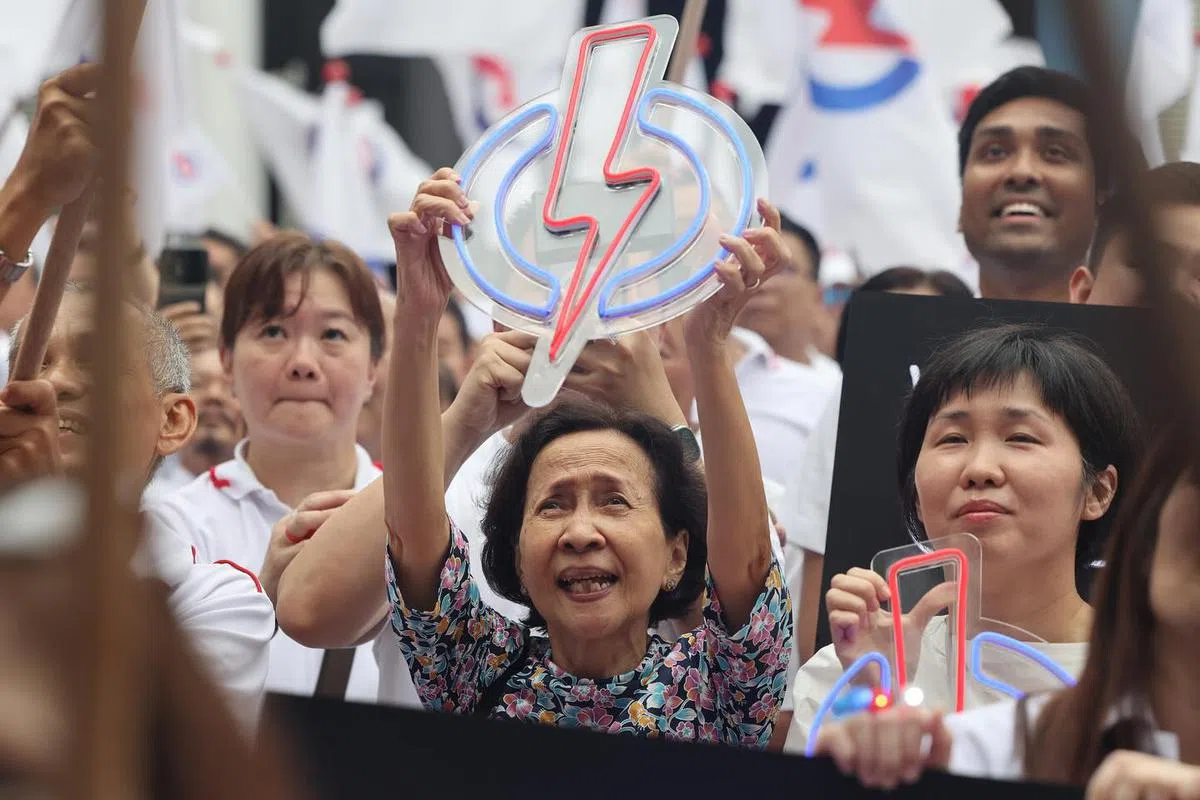 阿嬷手上的人民行动党标志，一看就是“演唱会同款”，一到晚上就会亮起的那种。看来是为晚上的群众大会准备的。（联合早报）